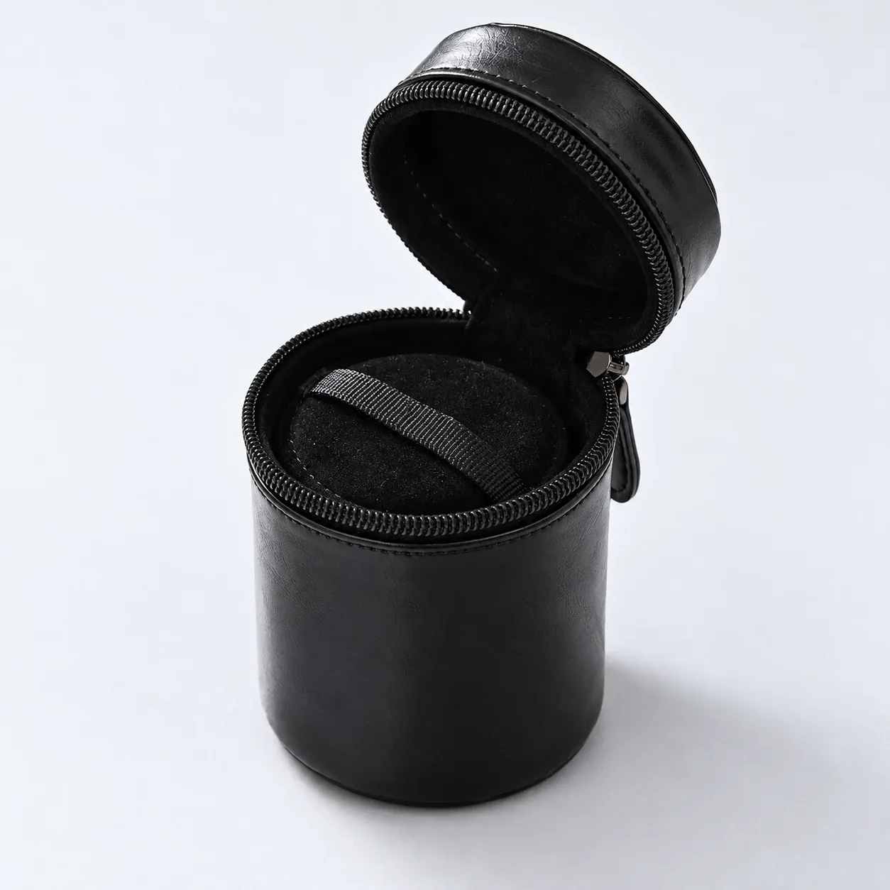 Open compact lens case showing its inner pad and pull tab